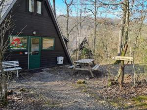 uma cabana com uma mesa de piquenique e um banco em frente a ela em Quiet Family Chalet in Durbuy Hills em Septon