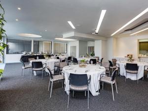 a banquet room with white tables and chairs at BreakFree on Cashel, an Accor Hotel in Christchurch