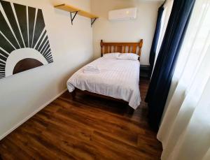 een kleine slaapkamer met een bed en een schilderij aan de muur bij Jarrah Cottage in Waroona