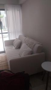 een witte bank in een woonkamer met een raam bij Max Suites block A, apartment 002 in Praia dos Carneiros