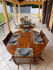 a wooden table with plates on it on a patio at Villa Jakéna à Sainte-Rose in Sainte-Rose