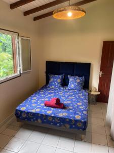 a bedroom with a bed with a red hat on it at Villa Jakéna à Sainte-Rose in Sainte-Rose