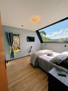a bedroom with a large window and a bed at Recanto do Tabuleiro chalé com hidro, lareira, churrasqueira e cozinha perto de floripa in Aguas Mornas