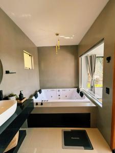 a large bathroom with a tub and a sink at Recanto do Tabuleiro chalé com hidro, lareira, churrasqueira e cozinha perto de floripa in Aguas Mornas +31 photos