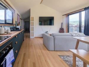 Sisters Beach Hideaway - A Coastal Escape في Sisters Beach: مطبخ وغرفة معيشة مع أريكة رمادية