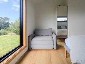 Sisters Beach Hideaway - A Coastal Escape في Sisters Beach: غرفة صغيرة بها كرسي ونافذة