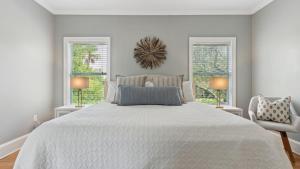 a white bedroom with a large bed and two windows at 3800 Cameron Boulevard AvantStay Pool Ocean Views Deck in Isle of Palms +88 photos