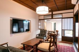 アトレチア祇園宇治別邸プレミアム في يوجي: غرفة معيشة مع طاولة وكراسي وتلفزيون