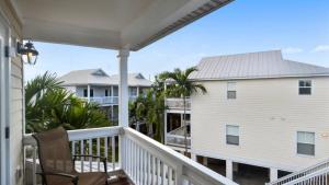 Coral Garden by AvantStay Great Location w Balcony Shared Pool في ستوك آيلاند: شرفة مع كرسي ومنزل