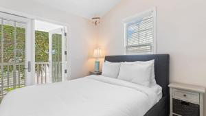 Coral Breeze by AvantStay Close to Beach w Balcony Shared Pool Month Long Stays Only في ستوك آيلاند: غرفة نوم بيضاء مع سرير ونافذة +17 صورة