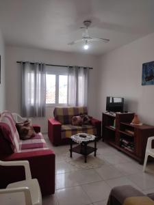 a living room with a couch and a tv at Casa Praia Arpoador in Peruíbe
