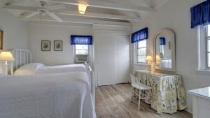 Un dormitorio blanco con una cama y una mesa. en 1111 Middle Street by AvantStay Charming Historic Cottage Featured in Dear John Movie Beach Access, en Sullivans Island