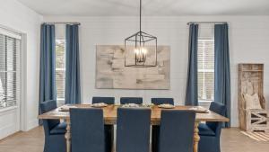 The Flying Pig by AvantStay Private Pool EV Charger Blue Mountain Luxury في شاطئ سانتا روزا: غرفة طعام مع طاولة خشبية وكراسي زرقاء