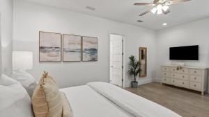 The Flying Pig by AvantStay Private Pool EV Charger Blue Mountain Luxury في شاطئ سانتا روزا: غرفة نوم بيضاء مع سرير وتلفزيون بشاشة مسطحة