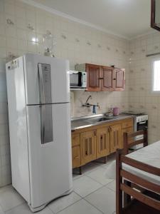 a kitchen with a white refrigerator and a sink at Casa Praia Arpoador in Peruíbe