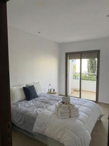 a bedroom with a large white bed with a window at 2BR Beach Apt, Pool, Luxury place in Mansouria