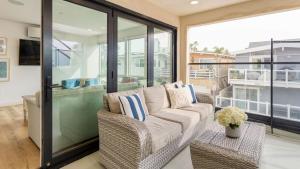 Velvet Sand I by AvantStay Steps to Newport Beach Private Rooftop w Outdoor Kitchen Hot Tub في شاطئ نيوبورت: غرفة معيشة مع أريكة وشرفة