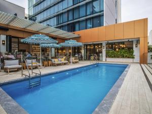 a pool in front of a building with umbrellas at The Adnate Perth - Art Series in Perth