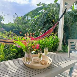 Villa Fleurs d'Air en côte sous le vent في ديساي: طاولة عليها أرجوحة وكأسين من النبيذ