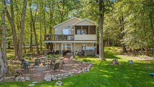 a house in the woods with a fire pit at Lake Daze by AvantStay Lakefront w Modern Interior Enclosed Porch Hot Tub in Long Pond