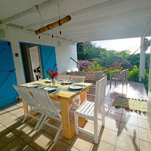 Villa Fleurs d'Air en côte sous le vent في ديساي: طاولة وكراسي خشبية على الفناء