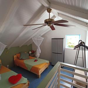 Villa Fleurs d'Air en côte sous le vent في ديساي: غرفة نوم بها سريرين ومروحة سقف