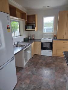 a kitchen with a white refrigerator and a sink at Accessible Respite House in Whangarei