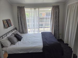 a bedroom with a bed and a large window at Accessible Respite House in Whangarei
