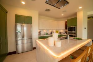 uma cozinha com armários verdes e uma geladeira de aço inoxidável em Terrazas 1A - 3 bedroom - seven day minimum em Isla Herradura