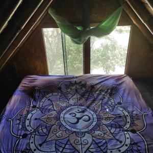a bed with a purple comforter in a room with a window at Wasi Center Homestay in Máncora +22 photos