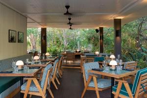 a dining room with wooden tables and chairs at Pinctada Hotel Broome in Broome
