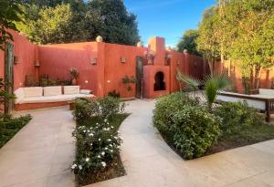 a garden with a red wall with a couch and a bench at Al Wadi Hôtel in Al Aqālitah +77 photos