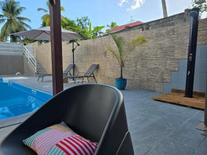 a black couch sitting next to a swimming pool at Détente absolue avec grande piscine in Les Abymes