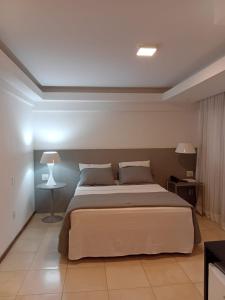 a bedroom with a large bed with two lamps on it at Suítes Executivas in Feira de Santana