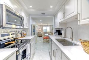 een keuken met witte kasten en een kookplaat oven bij Madeira Norte Beachfront Condo - Walk To John's Pass in St Pete Beach