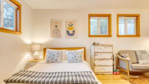 a bedroom with a bed and a chair and windows at Four Bears by AvantStay Walk to Beach Hot Tub Ocean View in Arch Cape