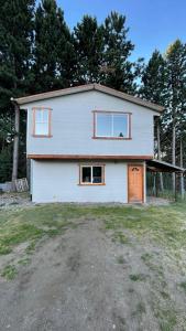 una casa blanca con ventanas y una puerta en Cabaña la percha II, en Coyhaique