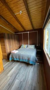 una cama en una habitación con techo de madera en Cabaña la percha II, en Coyhaique 1 foto más