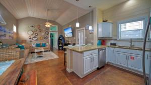 a kitchen with white cabinets and a living room at Shared Resort-Style Pool Playground Patio w Bar Tidal Times by AvantStay in Port Aransas