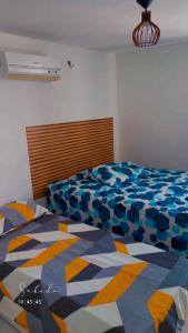 a bedroom with a bed with a colorful comforter at Mar e sol residencial 2 quartos com ar condicionado,500 metros da praia de Jacumã in Conde