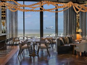 un restaurante con mesas y sillas y un avión despegando en Pullman Auckland Airport, en Auckland