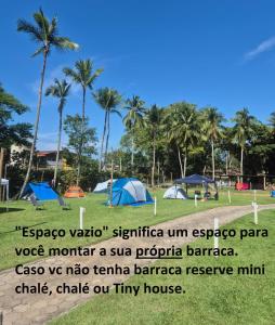 a group of tents in a park with palm trees at Camping & Cabanas Ilhabela in Ilhabela