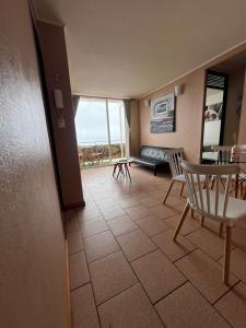 Departamento frente al mar في تومي: غرفة معيشة مع أريكة وطاولة وكراسي