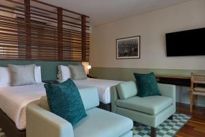 a hotel room with two beds and a chair at Pinctada Hotel Broome in Broome