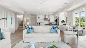 a living room and kitchen with a white couch and blue pillows at All Decked Out Seagrove by AvantStay Priv PoolHot Tub Ocean Views in Santa Rosa Beach