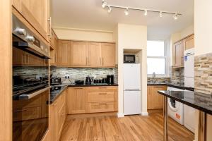 een keuken met houten kasten en een witte koelkast bij Heart of Looe Apartment in Looe