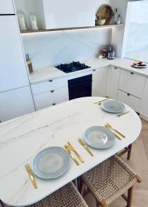 a white kitchen with a table with plates on it at Barbara's Beach House in Hallidays Point