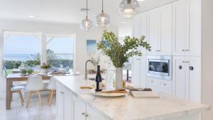 a kitchen with white cabinets and a table with wine bottles at Stardust by AvantStay Views Hot Tub Pool Table in Malibu