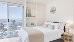 a white bedroom with a bed and a balcony at Stardust by AvantStay Views Hot Tub Pool Table in Malibu