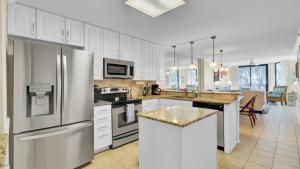 a kitchen with stainless steel appliances and a living room at 123D Shipwatch by AvantStay Beach Access Pool in Isle of Palms